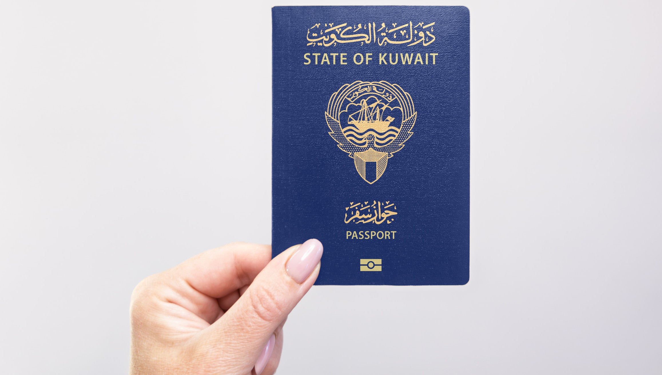 Hand holding a blue Kuwait passport